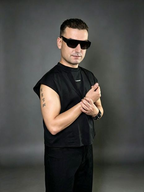 DJ TH de perfil, tatuagem no braço