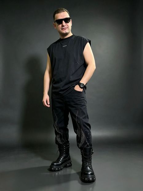 DJ TH sentado, coturnos e look all black